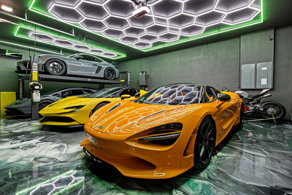 Garage with an orange McLaren under HexGlow hexagon lights with a green border